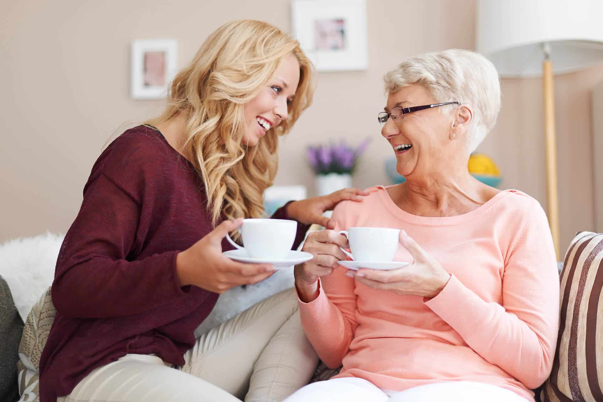 Caregiver speaking with an older woman on a sofa