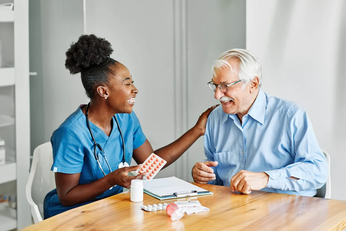 Caregiver and older man sharing a meal at home