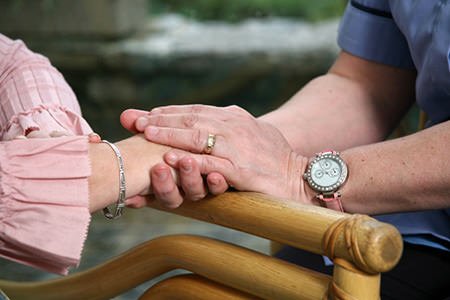 Hands supporting an older person’s hand