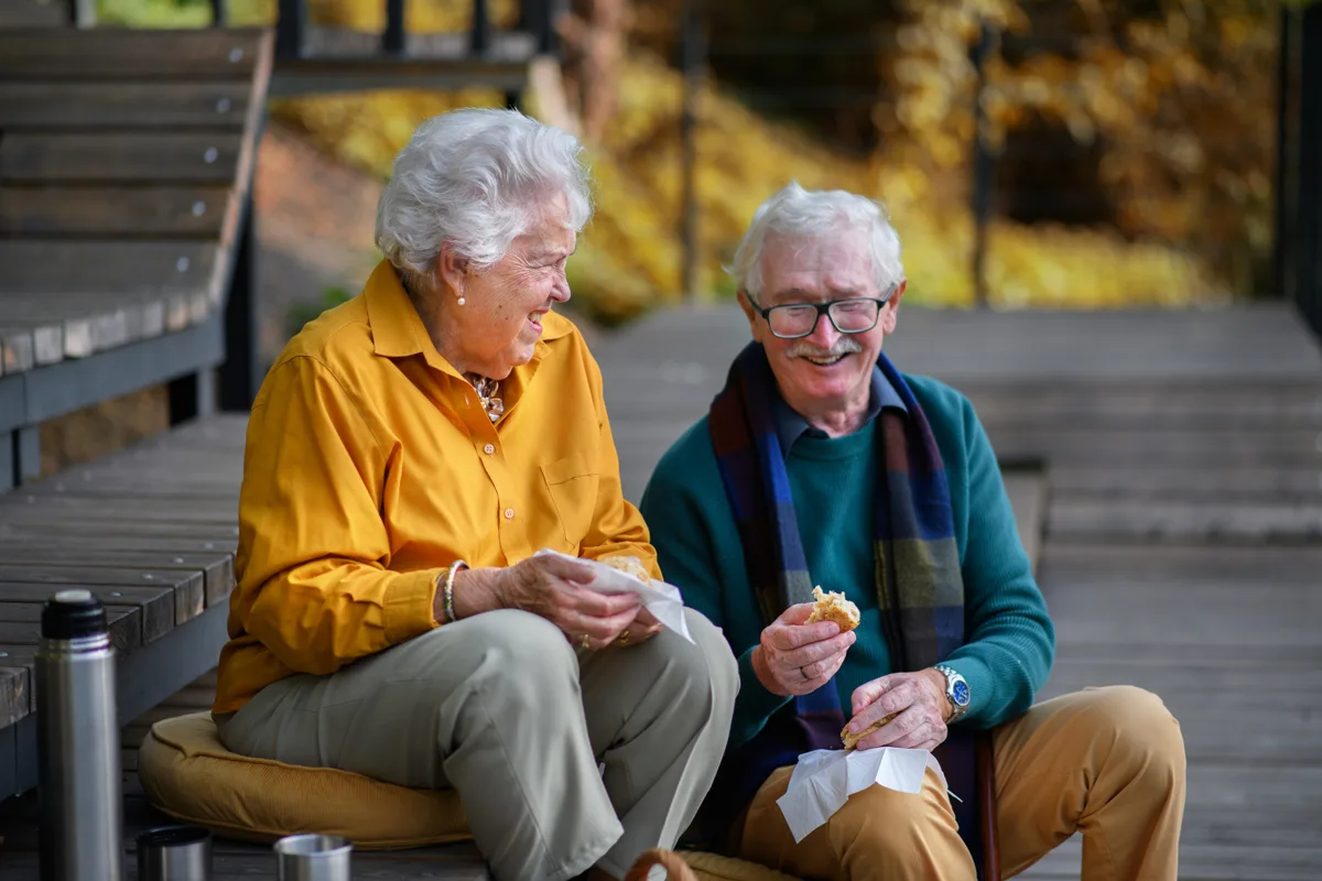 Older couple reading together on a park bench