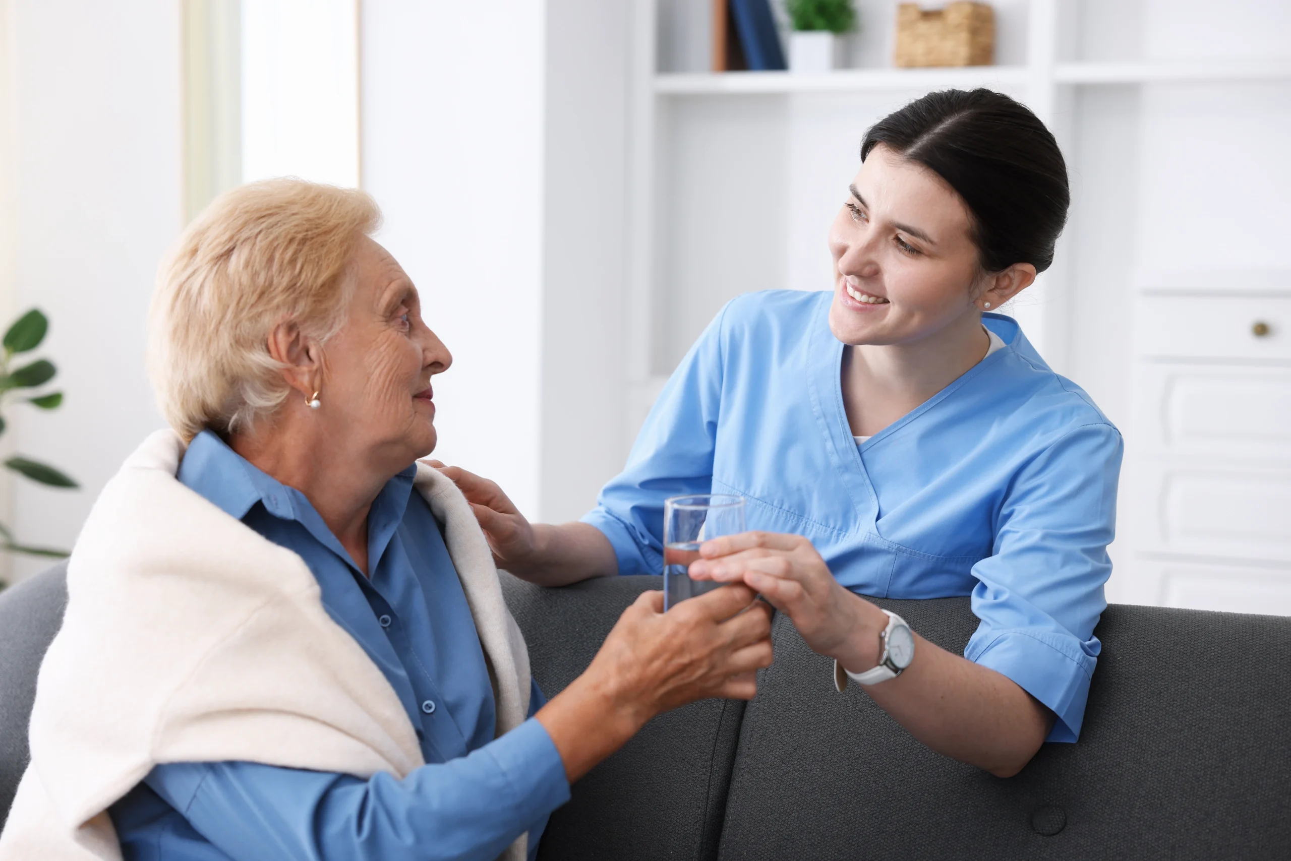 nurse giving glass of water to senior woman